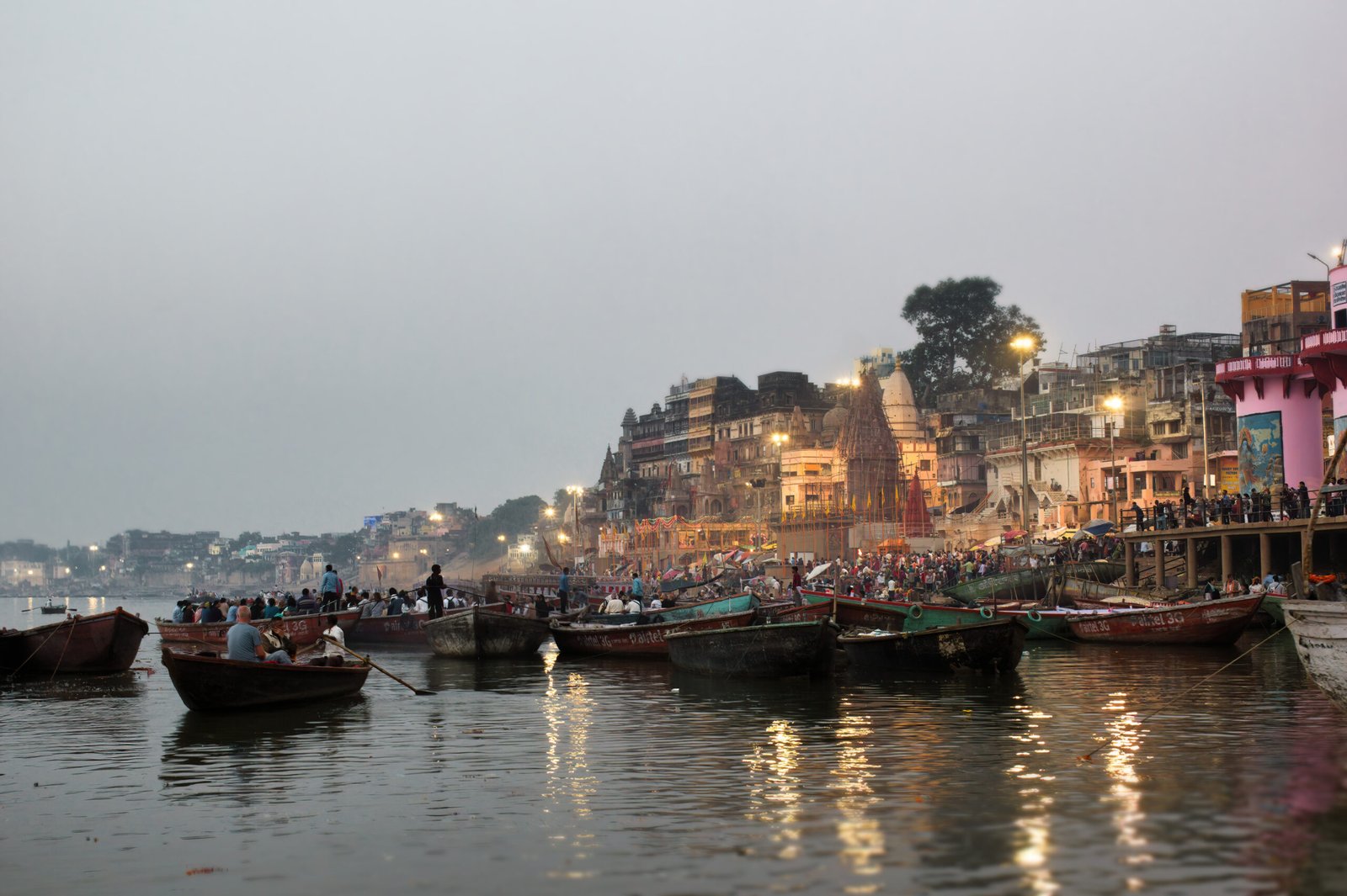 Varanasi, India - November 01, 2016: Boats at river Ganga Ghat people at holy ghats among ancient hindu temples in early morning in Varanasi or ancient Banaras city India Assi Ghat Aarti ceremony at Ganga River Evening at Banaras ghat ancient wooden boats